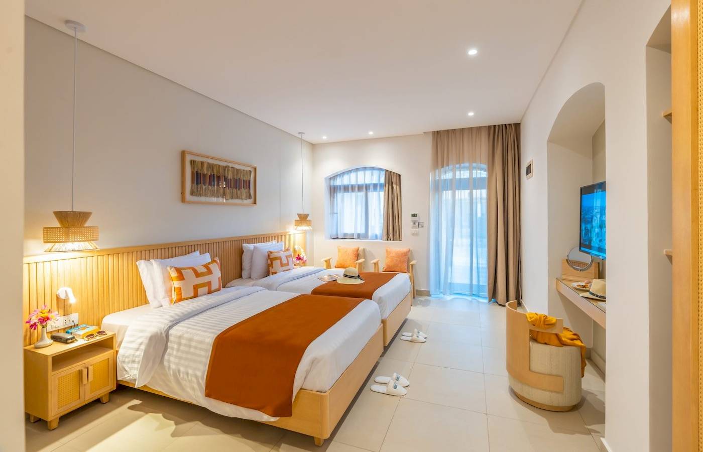 Innenansicht eines Doppelzimmers im Three Corners Rihana Resort mit zwei Betten, Dekor und Fenstern.