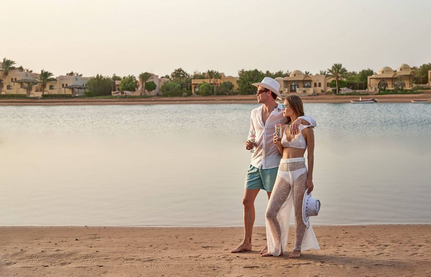 Paar am Strand des Three Corners Rihana Resorts mit Blick auf Wasser und Gebäude
