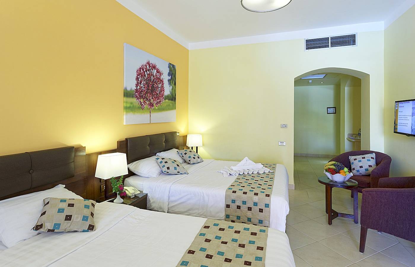 Doppelzimmer-Innenansicht im Three Corners Rihana Resort mit zwei Betten und gelben Wänden.