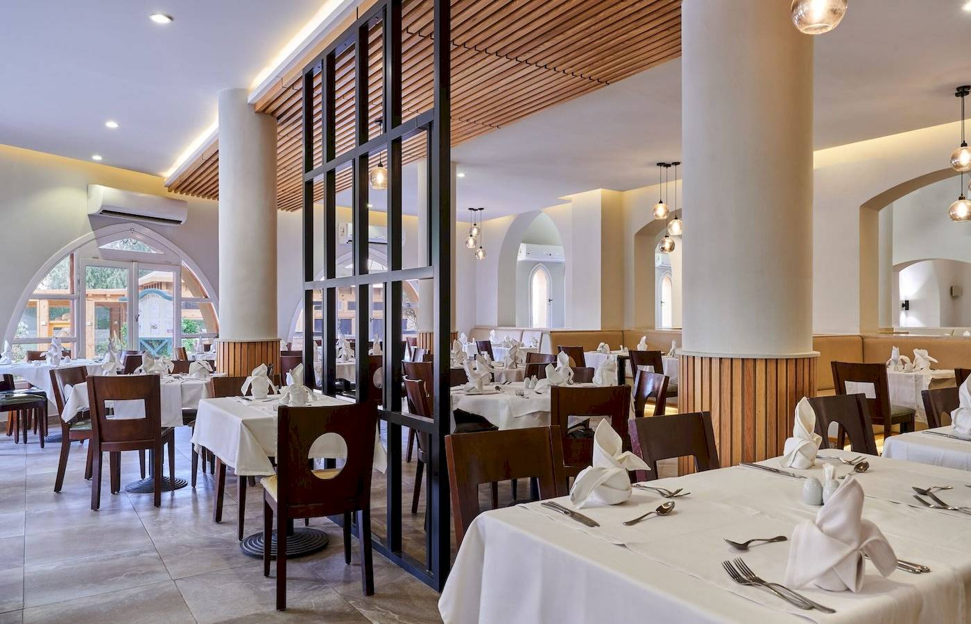 Innenansicht des Restaurants im Three Corners Rihana Resort mit gedeckten Tischen und Stühlen.