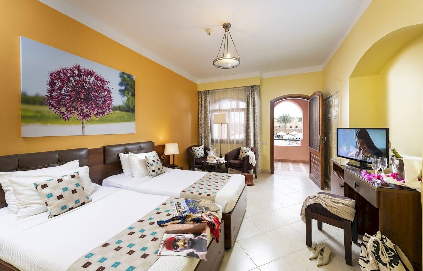 Doppelzimmer im Three Corners Rihana Resort mit zwei Betten, Fernseher und Möbeln.