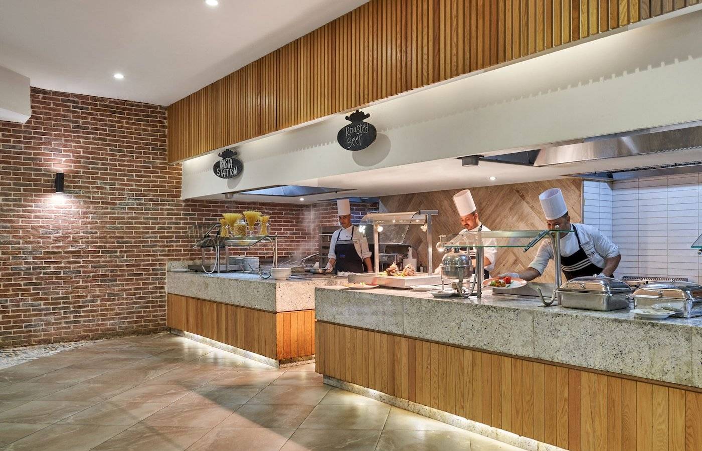 Kueche im Three Corners Rihana Resort mit drei Kochen in weissen Muetzten