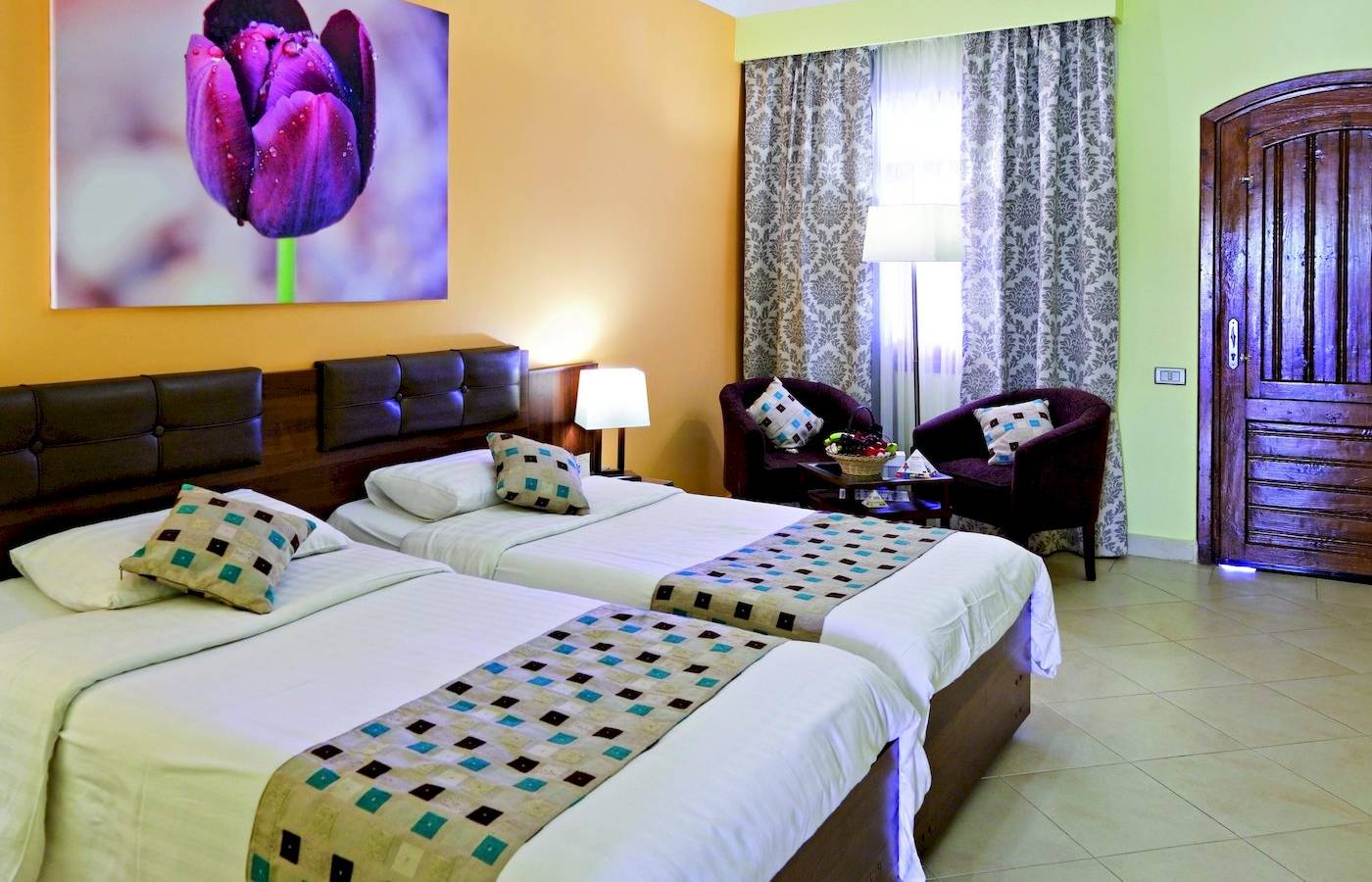 Zwei Betten im Zimmer im Three Corners Rihana Resort mit gemusterten Laken und Kissen.