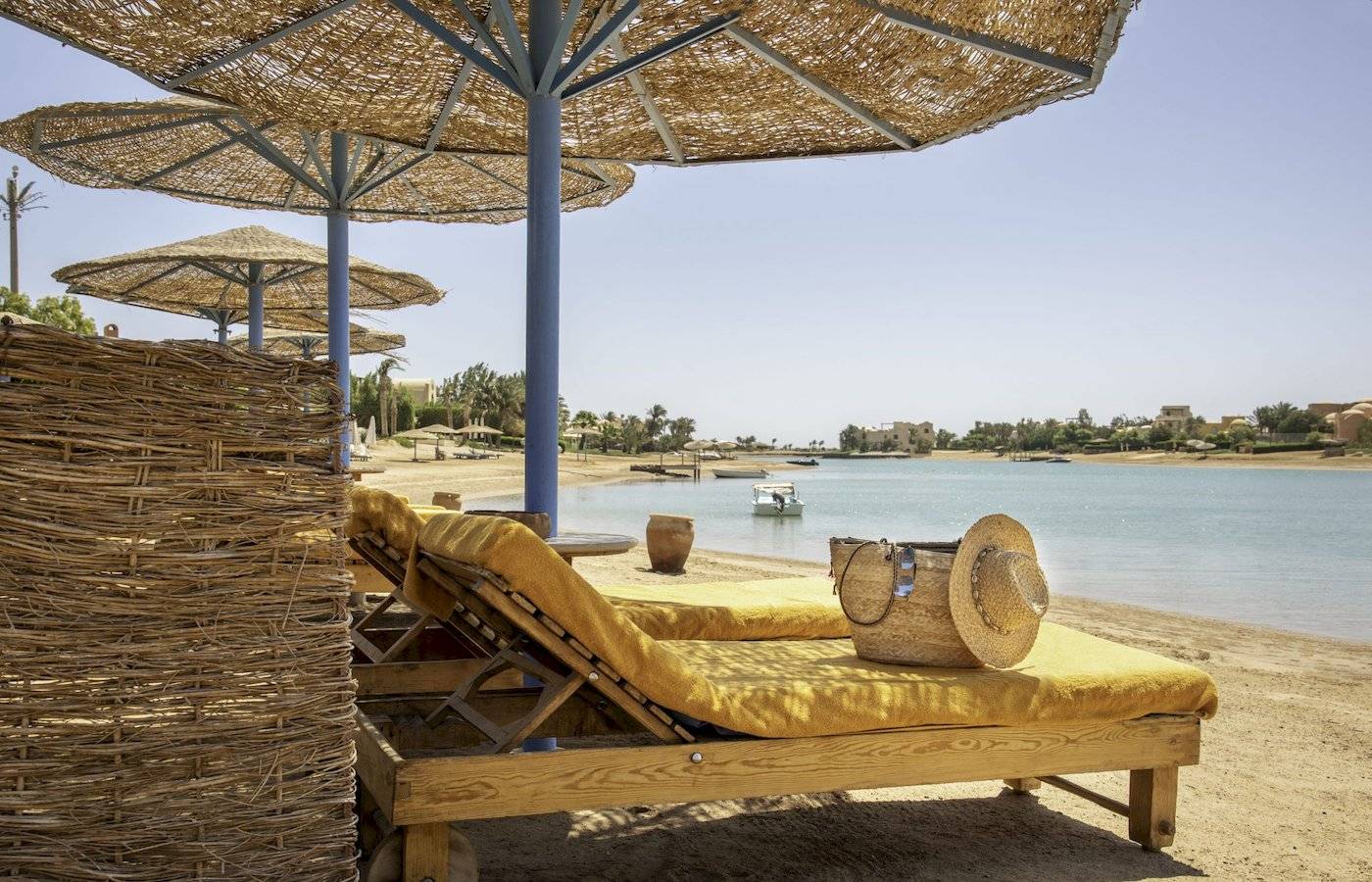 Strandszene im Three Corners Rihana Resort mit Liegen, Sonnenschirmen und einem Blick aufs Wasser.