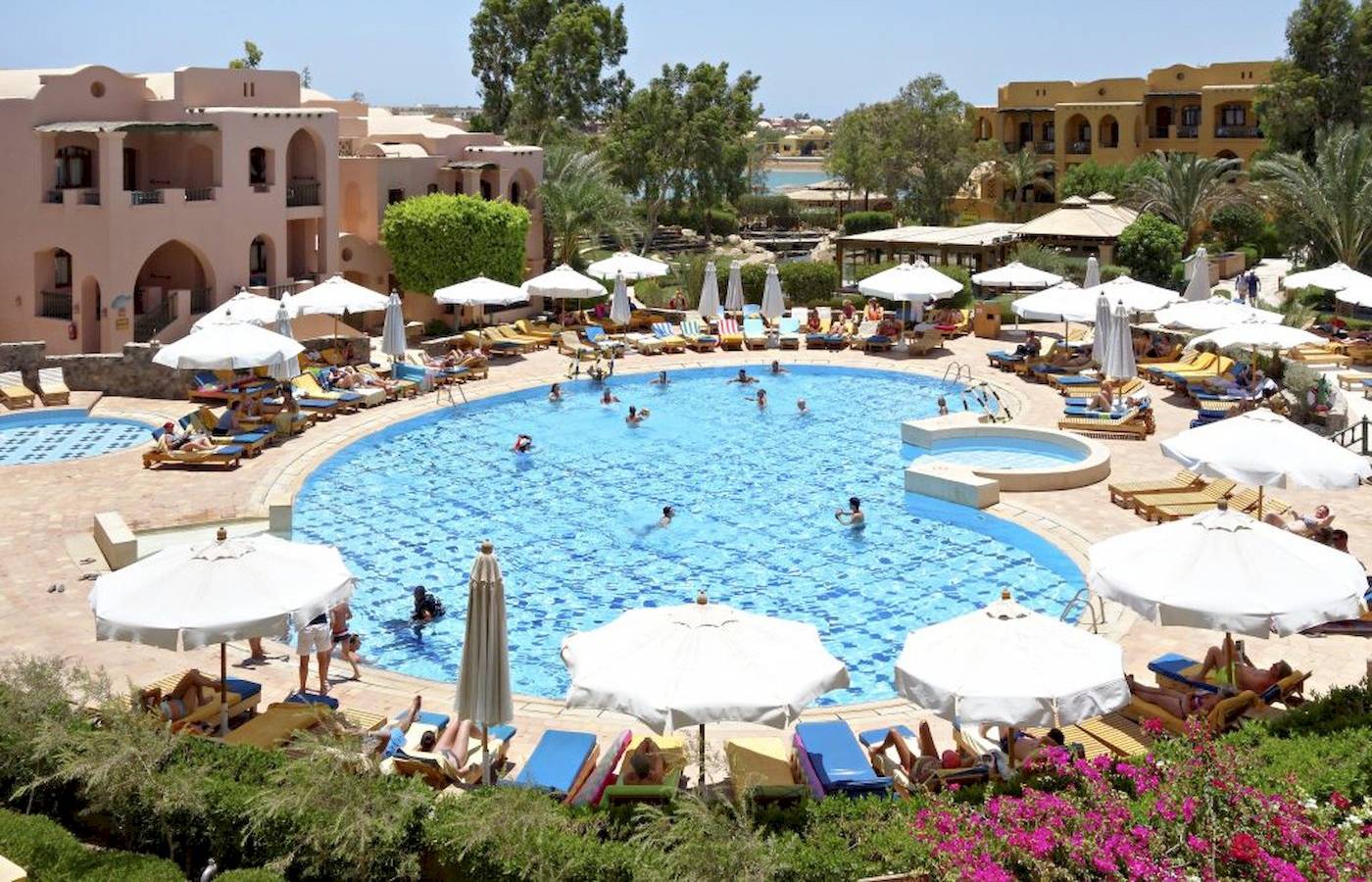 Poolbereich des Three Corners Rihana Resorts mit vielen Gästen und Sonnenschirmen