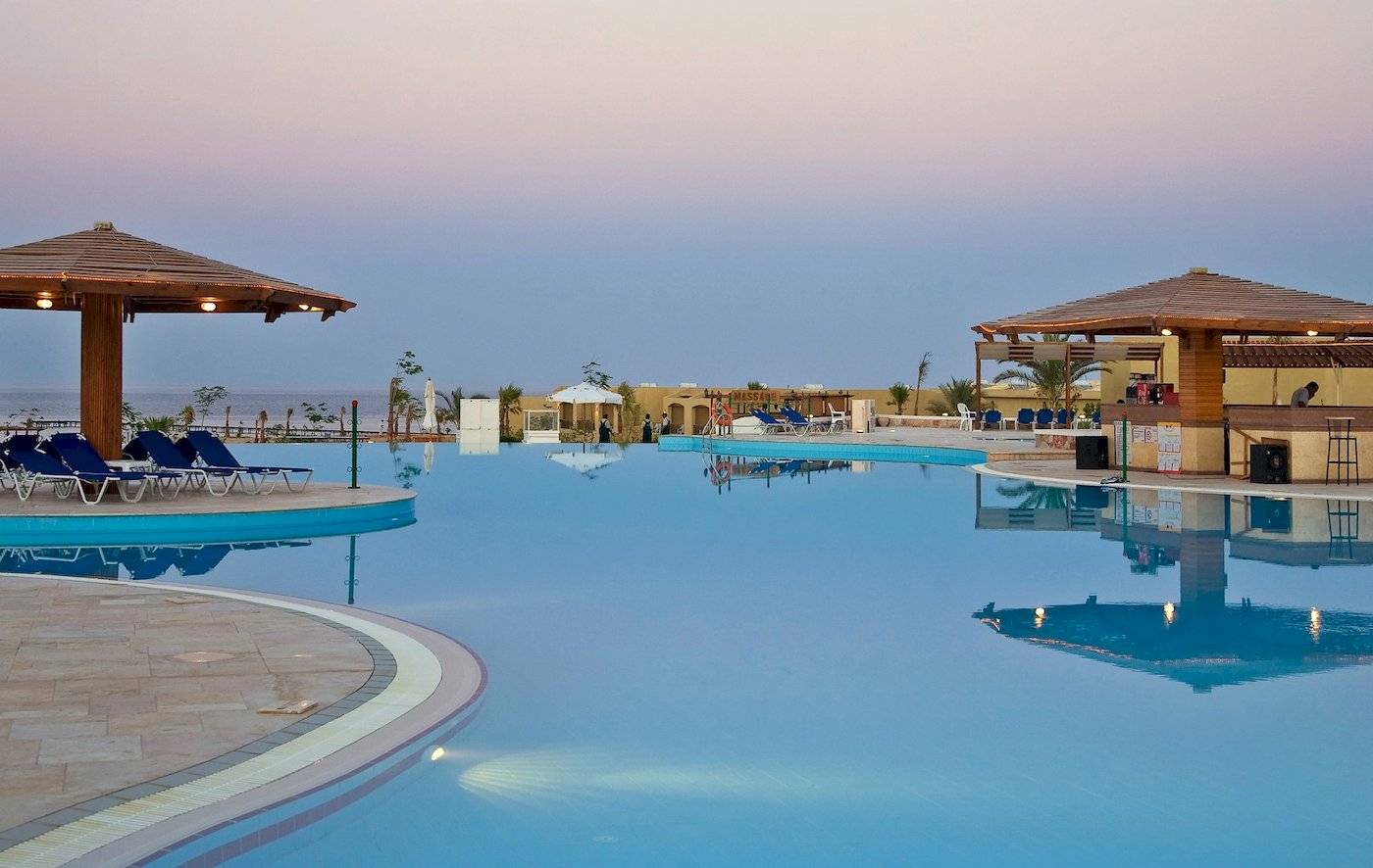 Ein Swimmingpool des Three Corners Fayrouz Plaza Beach Resorts bei Sonnenuntergang.