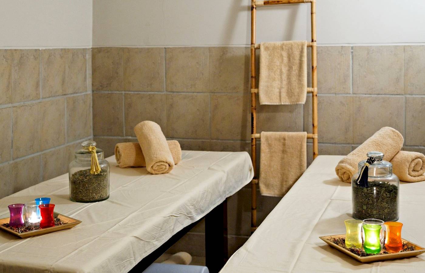 Massageraum im Three Corners Fayrouz Plaza Beach Resort mit zwei Massagetischen, Kerzen und Handtüchern.