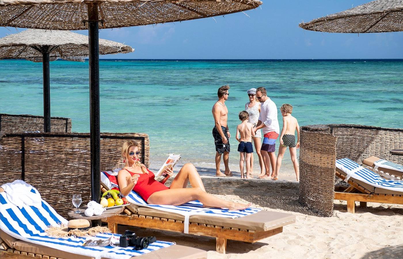 Eine Frau liest ein Buch auf einem Liegestuhl am Strand des Three Corners Fayrouz Plaza Beach Resort.