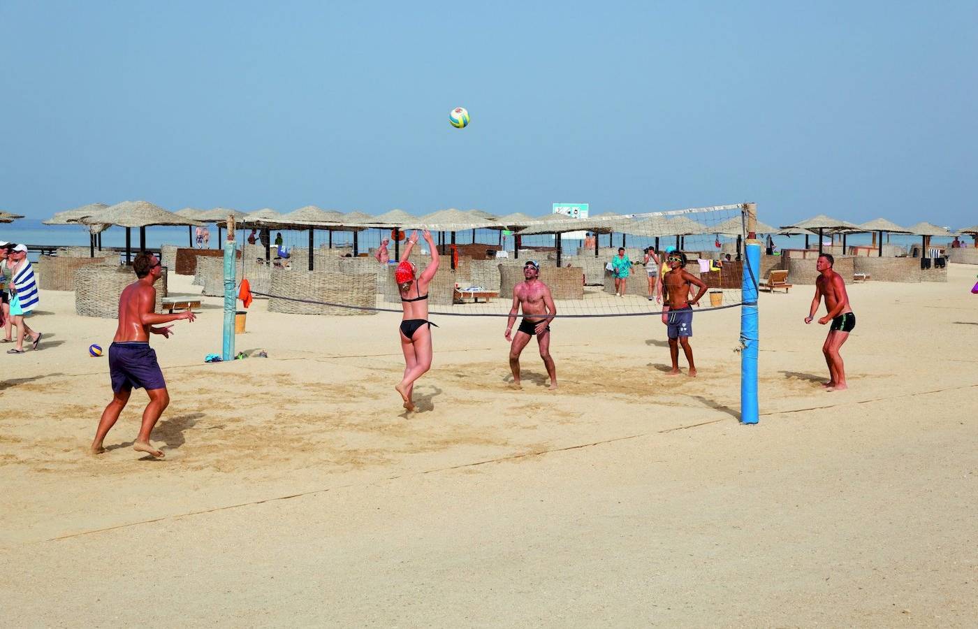 Mehrere Männer spielen Volleyball am Strand des Three Corners Fayrouz Plaza Beach Resort.