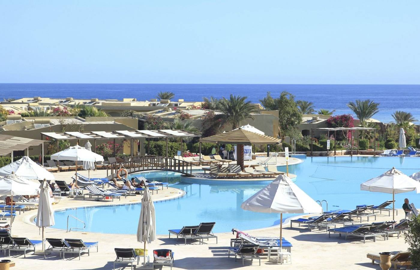 Außenbereich des Three Corners Fayrouz Plaza Beach Resort mit Pool, Liegestühlen und Sonnenschirmen.