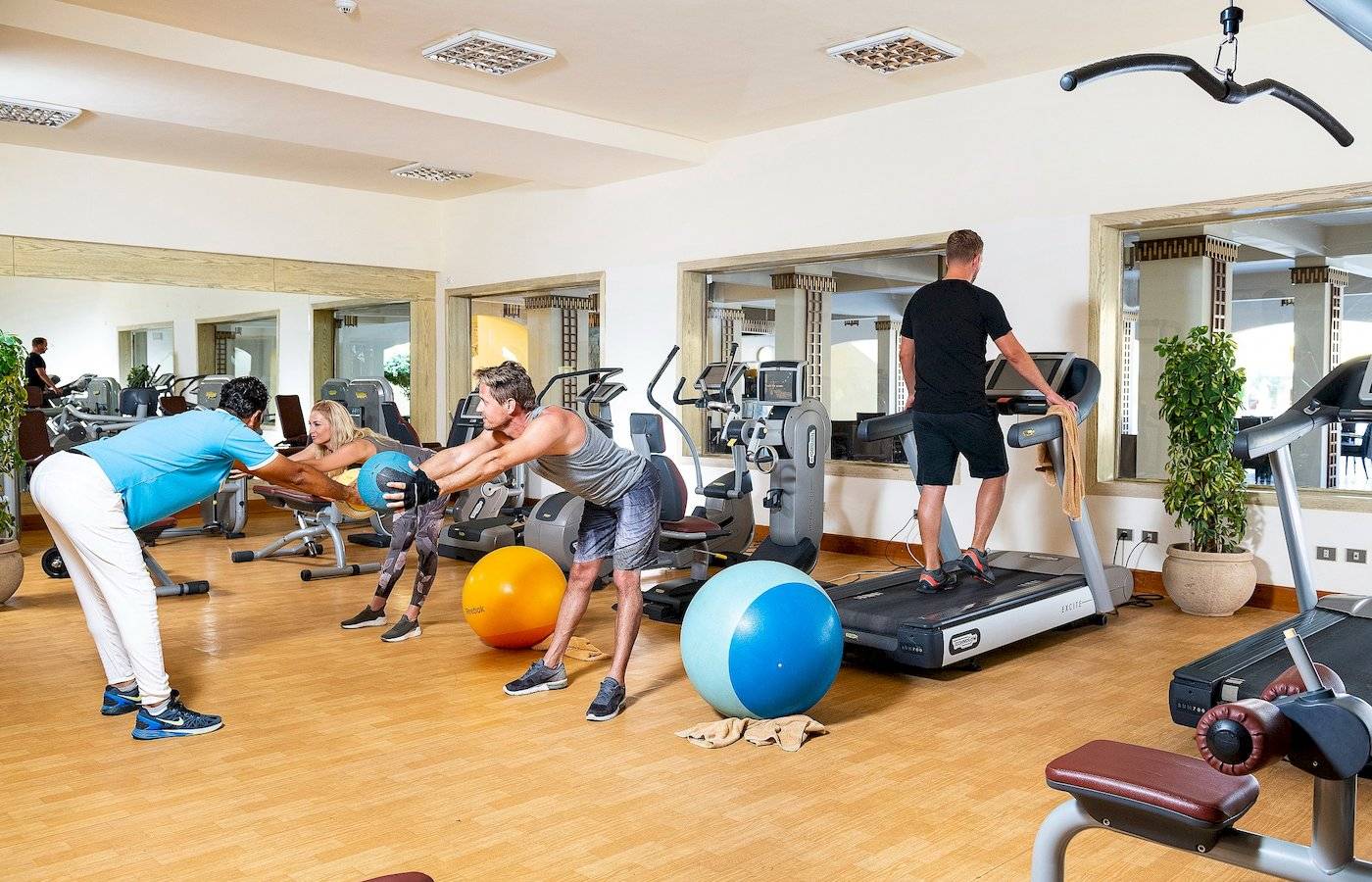 Fitnessstudio im Three Corners Fayrouz Plaza Beach Resort mit Personen, die an Geräten trainieren.