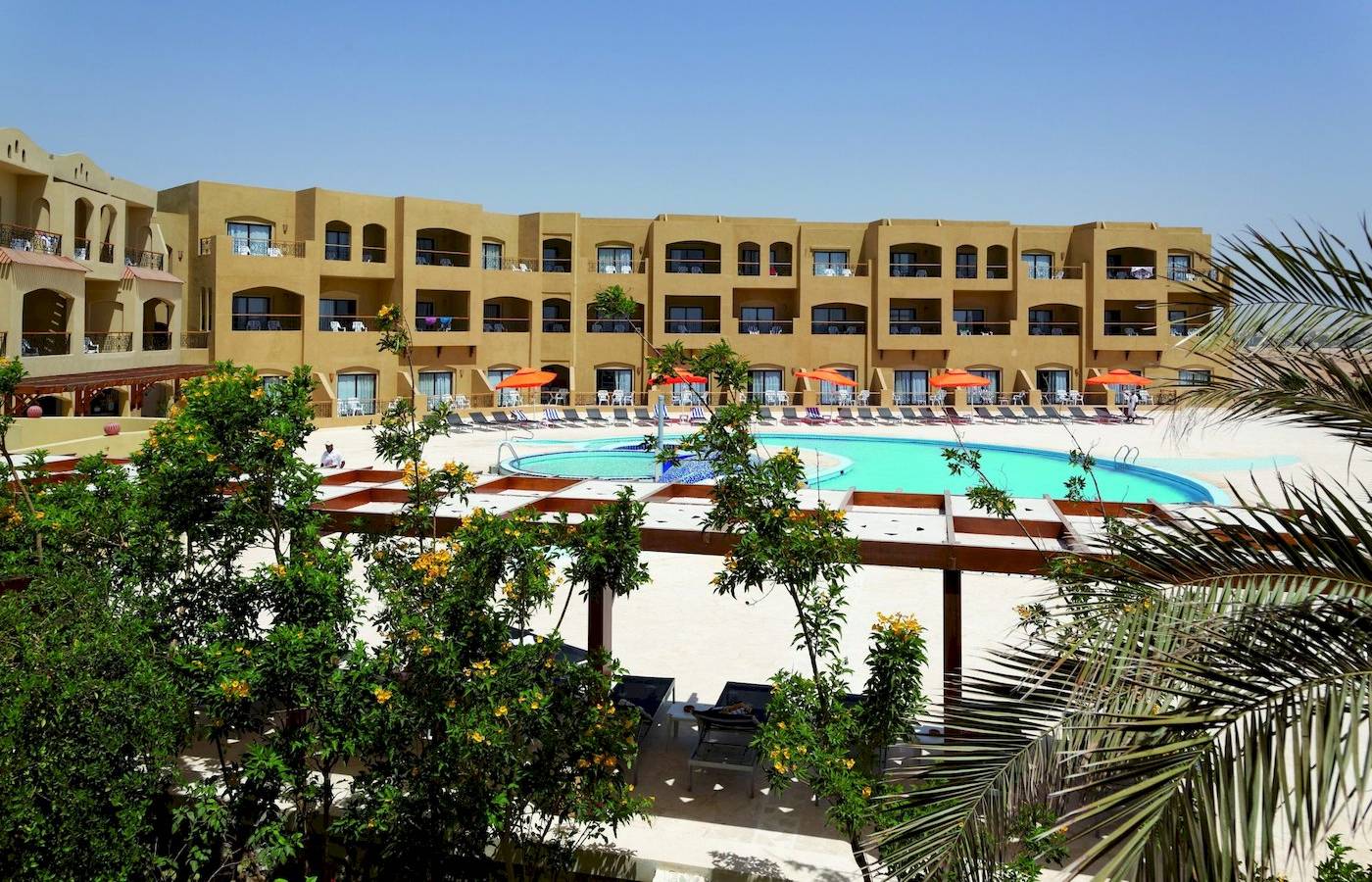 Außenbereich des Three Corners Fayrouz Plaza Beach Resorts mit Swimmingpool und Sonnenschirmen.