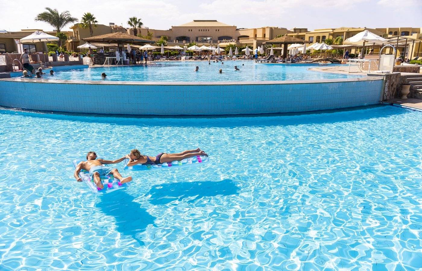 Ein Paar liegt auf Schwimmringen im Pool des Three Corners Fayrouz Plaza Beach Resorts.