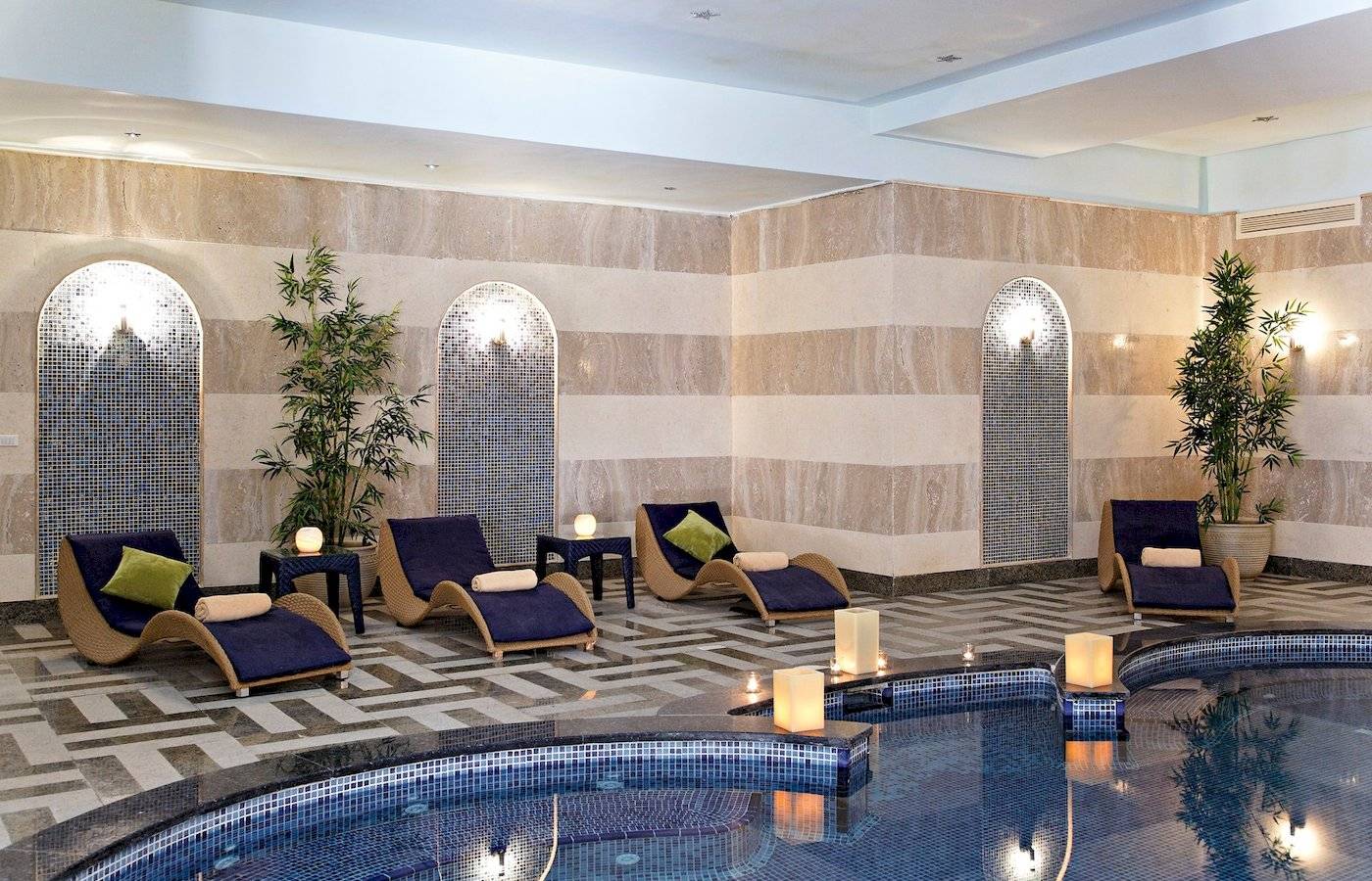 Pool-Bereich im Three Corners Fayrouz Plaza Beach Resort mit Liegen und blauen Kissen.