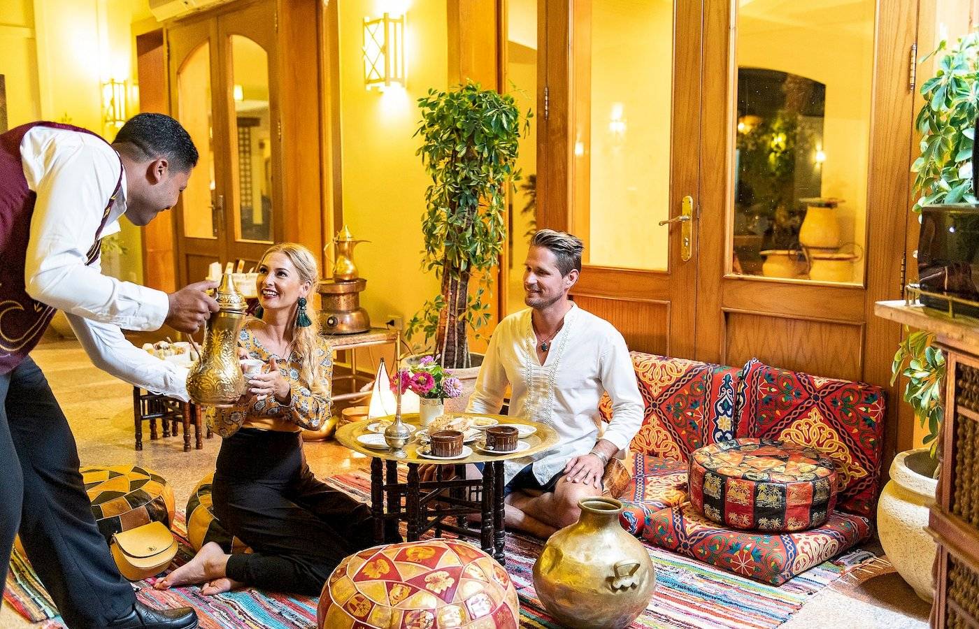 Ein Hotelmitarbeiter serviert ein Paar im Drei Ecken Fayrouz Plaza Strand Resort.