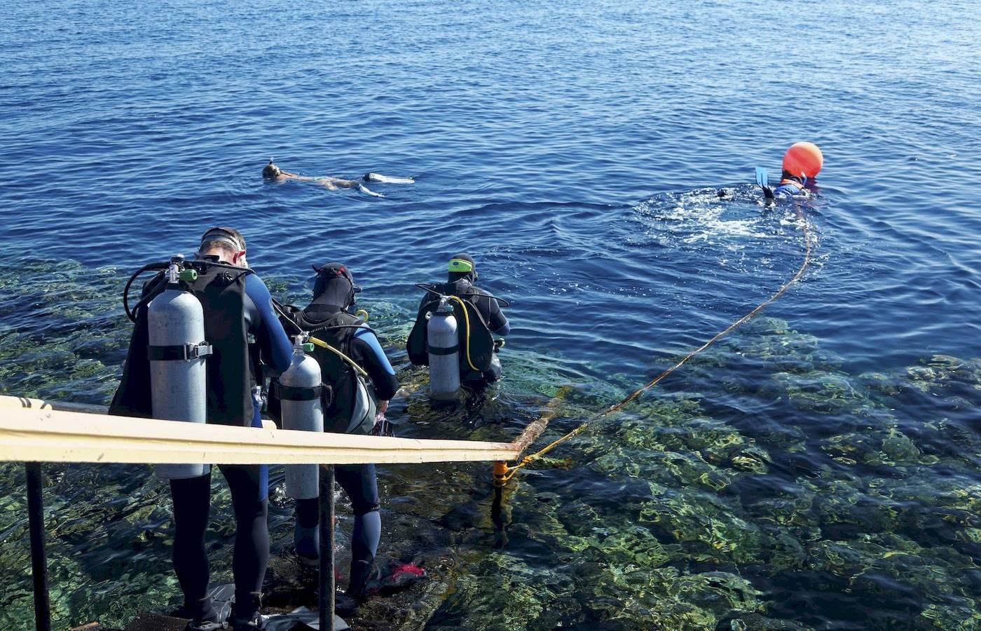 Scuba-Taucher in Schutzausrüstung, die das Meer betreten, um zu tauchen.