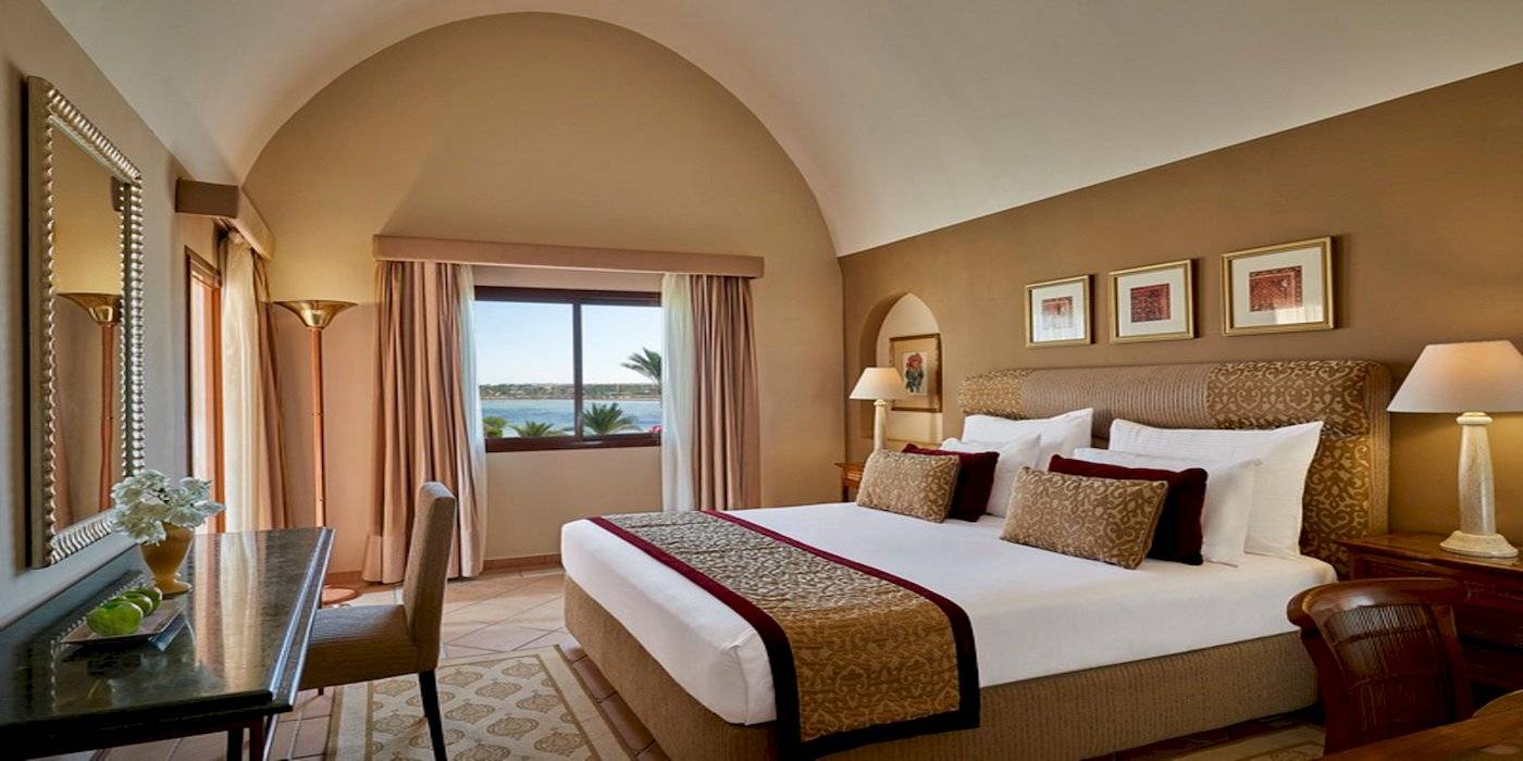 Schlafzimmer im Steigenberger Coraya Beach Hotel mit Blick auf das Meer und Palmen.