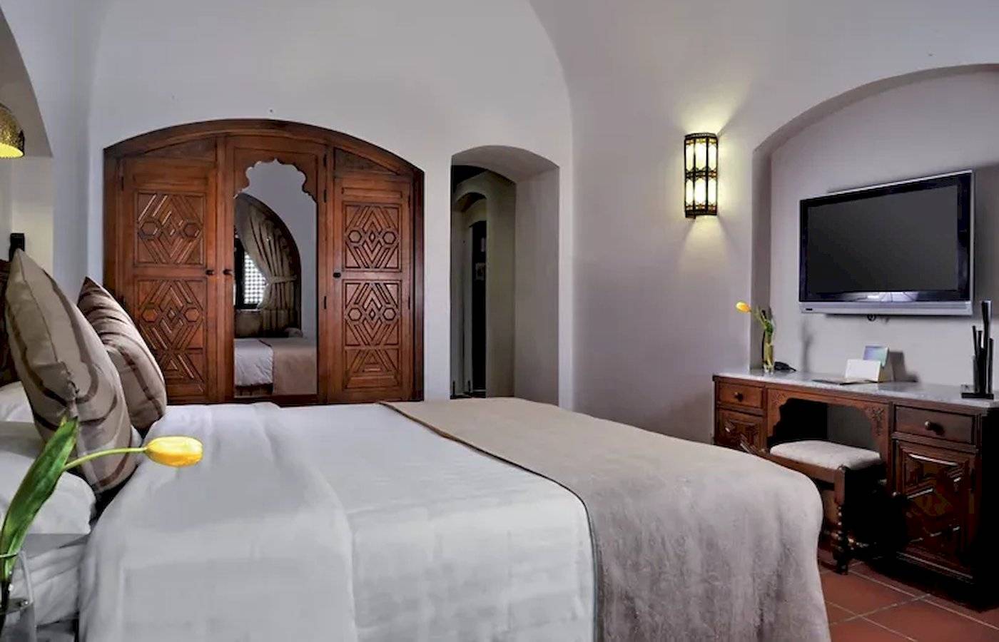 Schlafzimmer im Mövenpick Resort Sharm el Sheikh mit einem Bett, einem Fernseher und einem Schreibtisch.