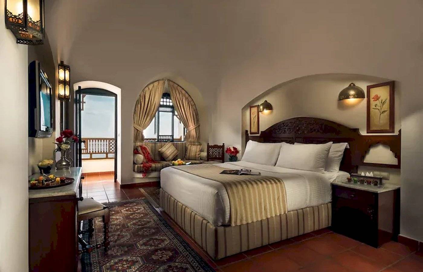 Innenansicht eines Suite-Zimmers im Mövenpick Resort Sharm el Sheikh mit einem großen Bett und einer gemütlichen Sitzecke.