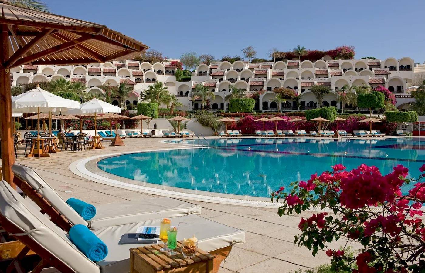 Außenpool des Mövenpick Resort Sharm el Sheikh mit Loungeliegen und Sonnenschirmen