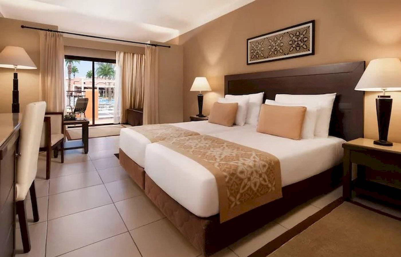 Doppelbett-Zimmer im JAZ Neo Dar El Madina Hotel mit gemusterten Laken, zwei Nachttischen und Lampen.