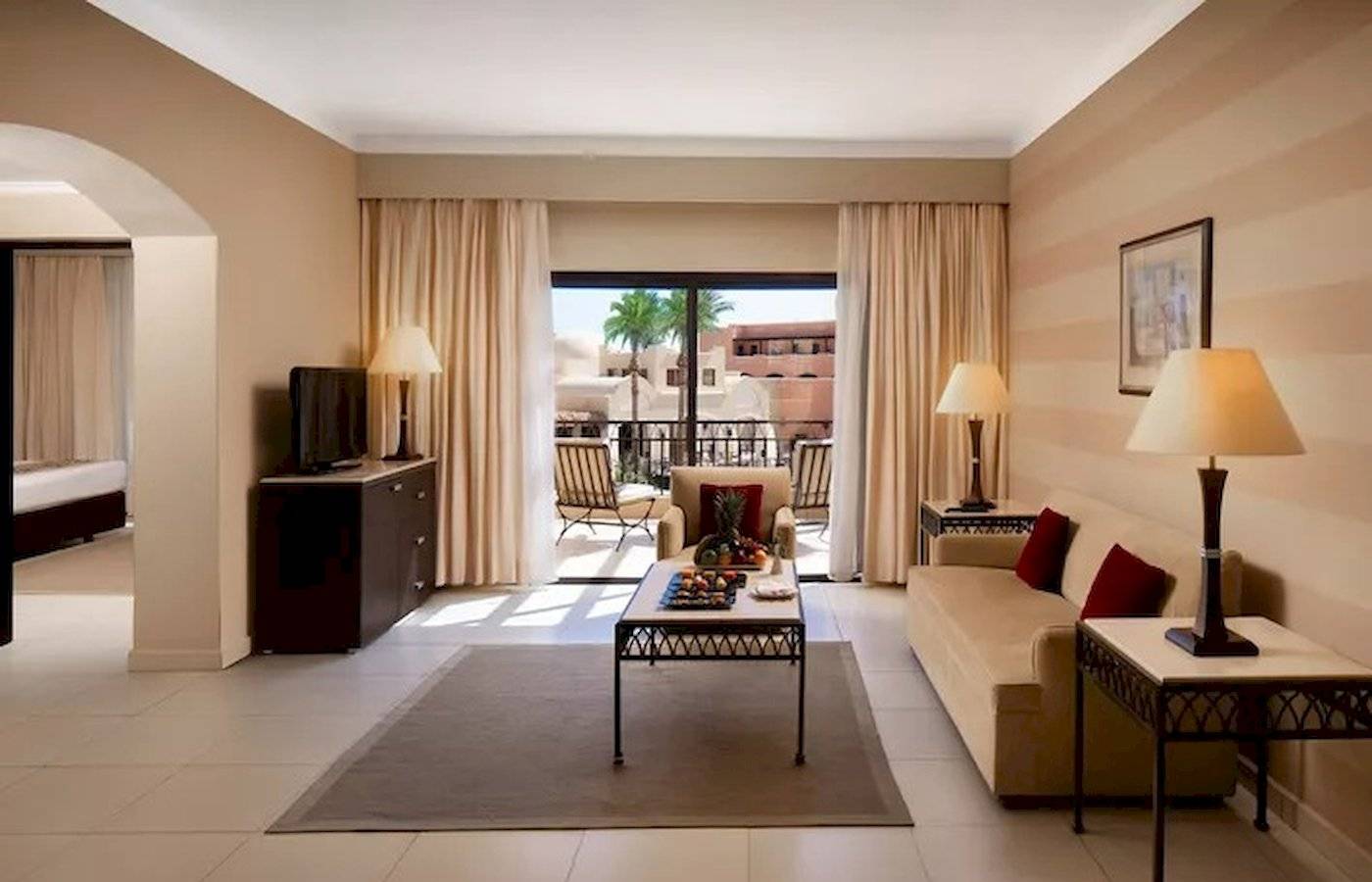 Innenansicht der Suite im JAZ Neo Dar El Madina Hotel mit Wohnzimmer, Couch, Tisch und Balkon.