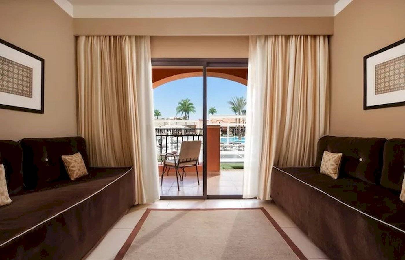 Innenansicht einer Suite im JAZ Neo Dar El Madina Hotel mit Möbeln und Glastür.