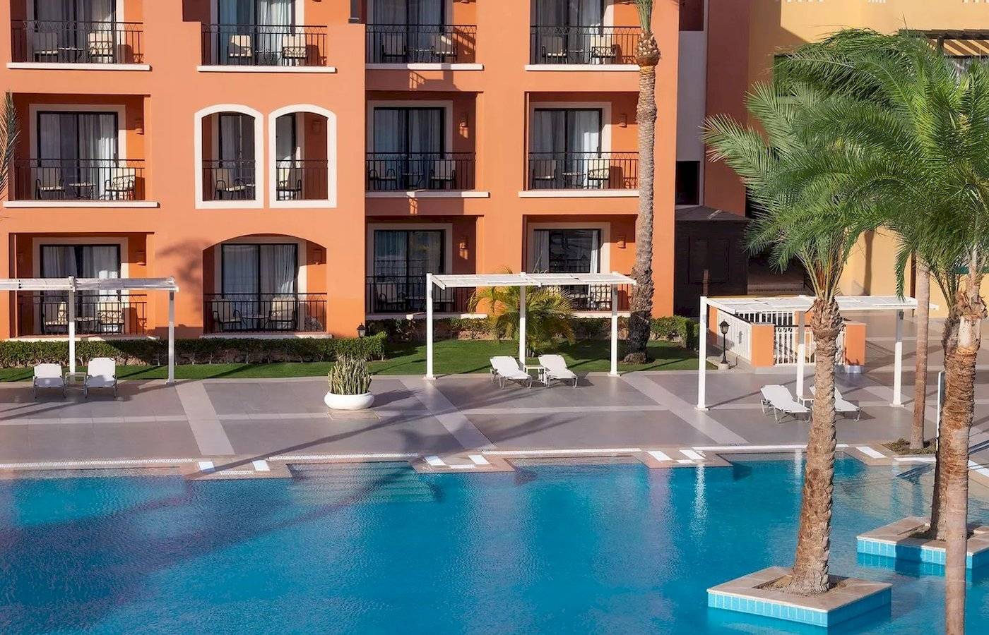 Außenbereich des JAZ Neo Dar El Madina Hotels mit Swimmingpool und Sonnenliegen.