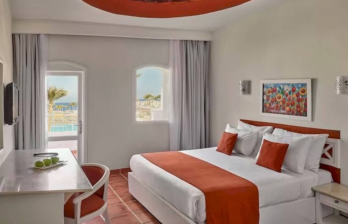 Innenansicht eines Zimmers im Jaz Neo Reef Marsa mit einem Bett, Schreibtisch, Fenster und Meerblick.