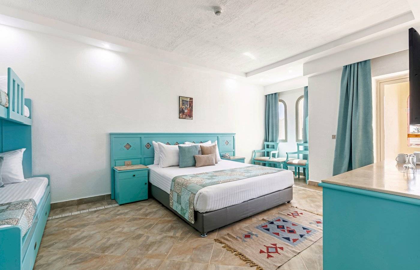 Hotelzimmer im Sunrise Royal Makadi Resort mit Doppelbett, zwei Einzelbetten und grünen Möbeln.