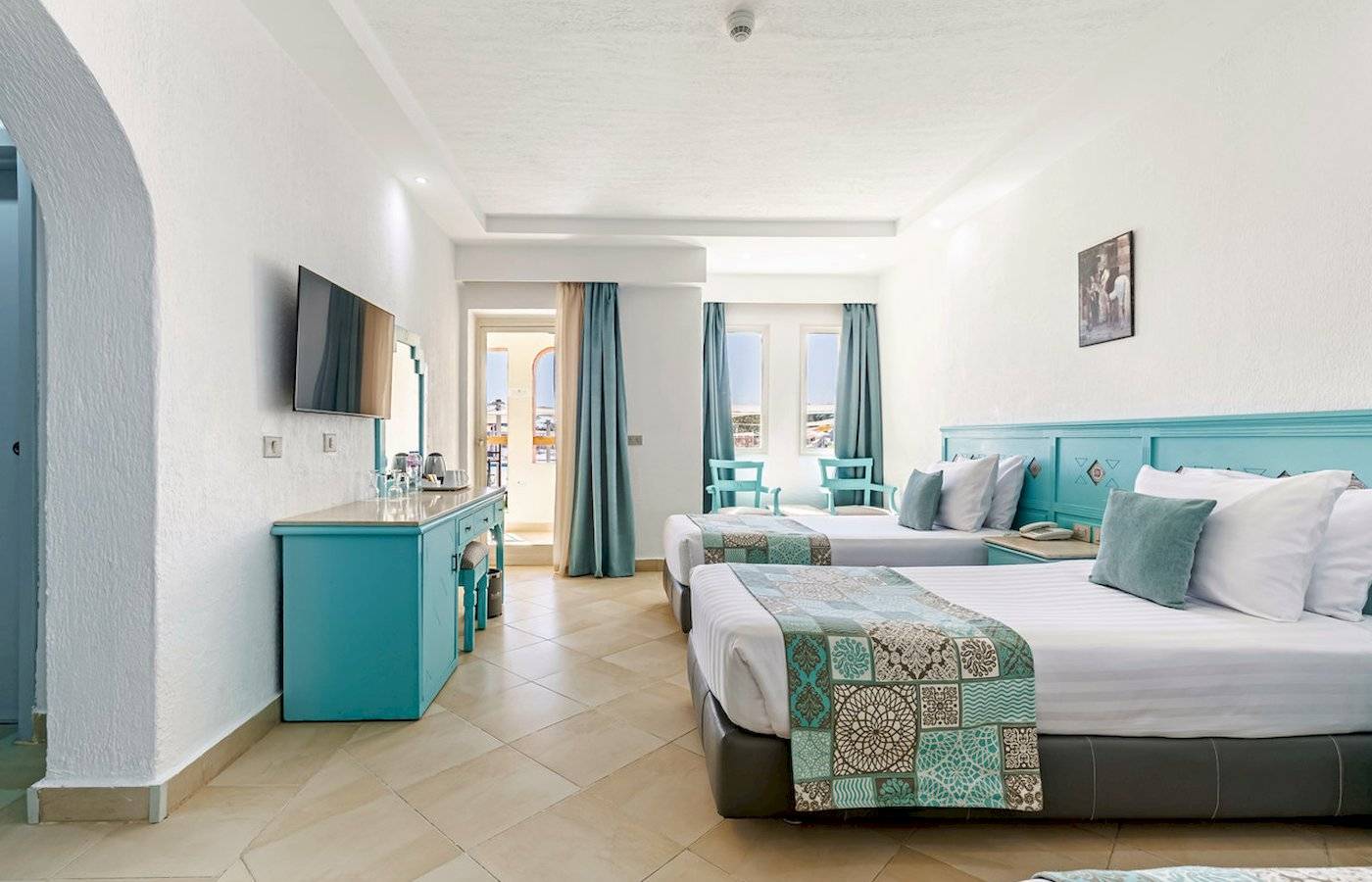 Zimmer im Sunrise Royal Makadi Resort mit zwei Betten und türkisfarbener Einrichtung