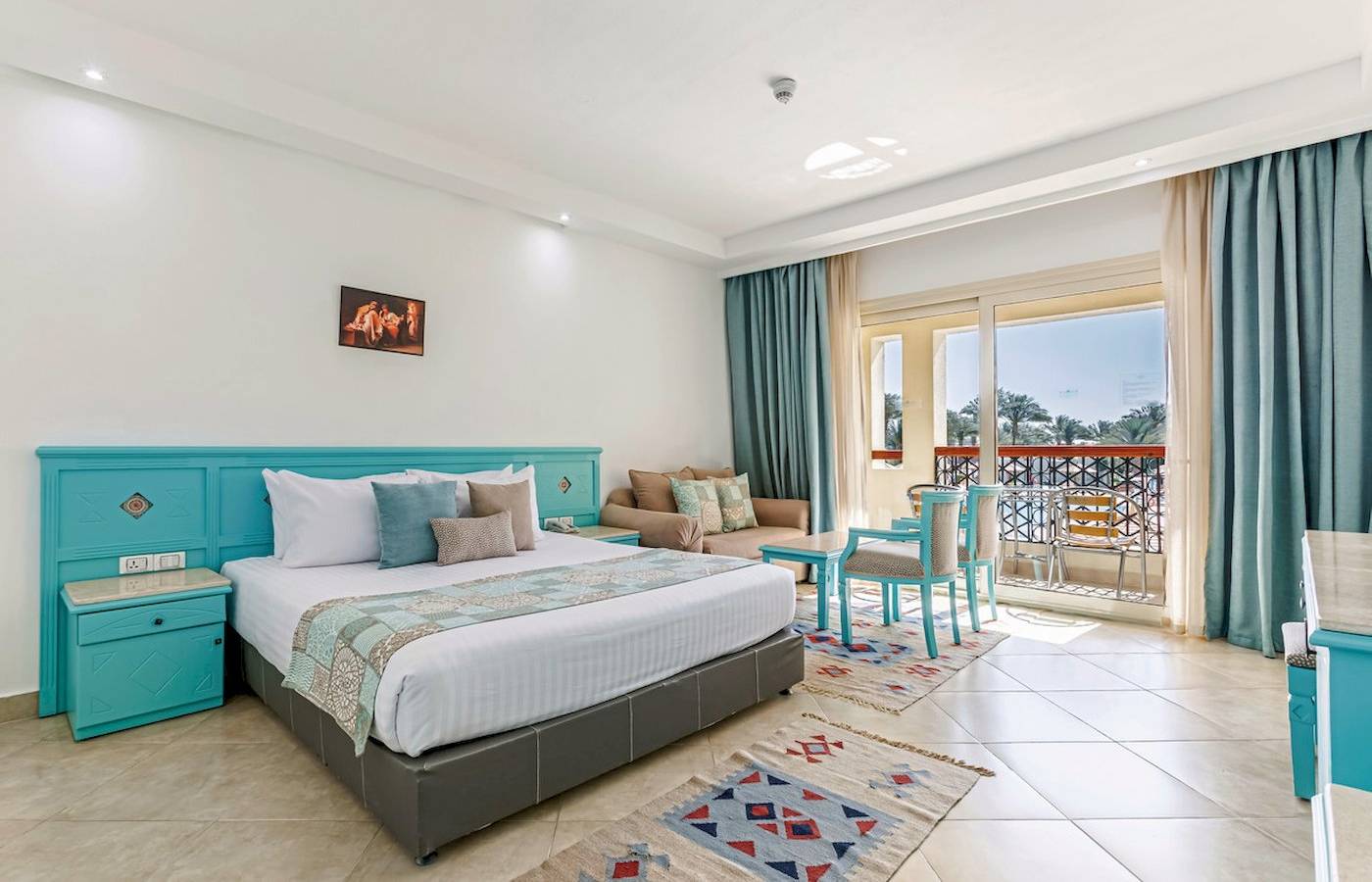 Hotelzimmer im Sunrise Royal Makadi Resort mit Bett, Nachttischen und Balkon.