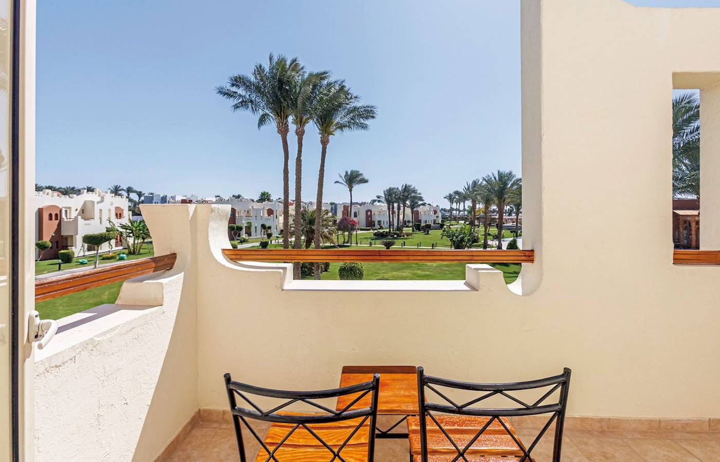Ein Balkon des SUNRISE Royal Makadi Resort mit Blick auf Palmen und einen Garten.