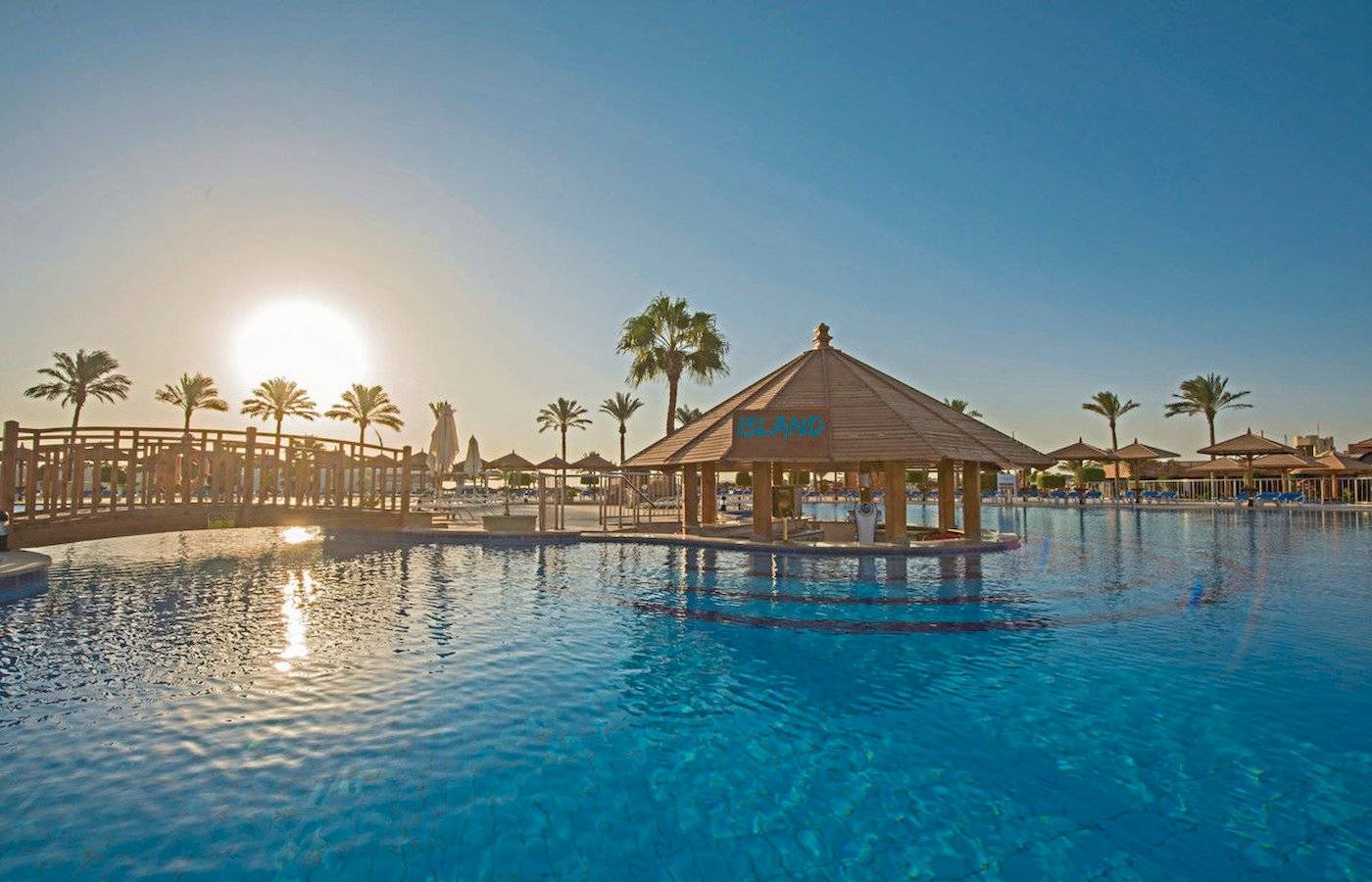 Außenpool im Sunrise Royal Makadi Resort mit Sonnenuntergang im Hintergrund.