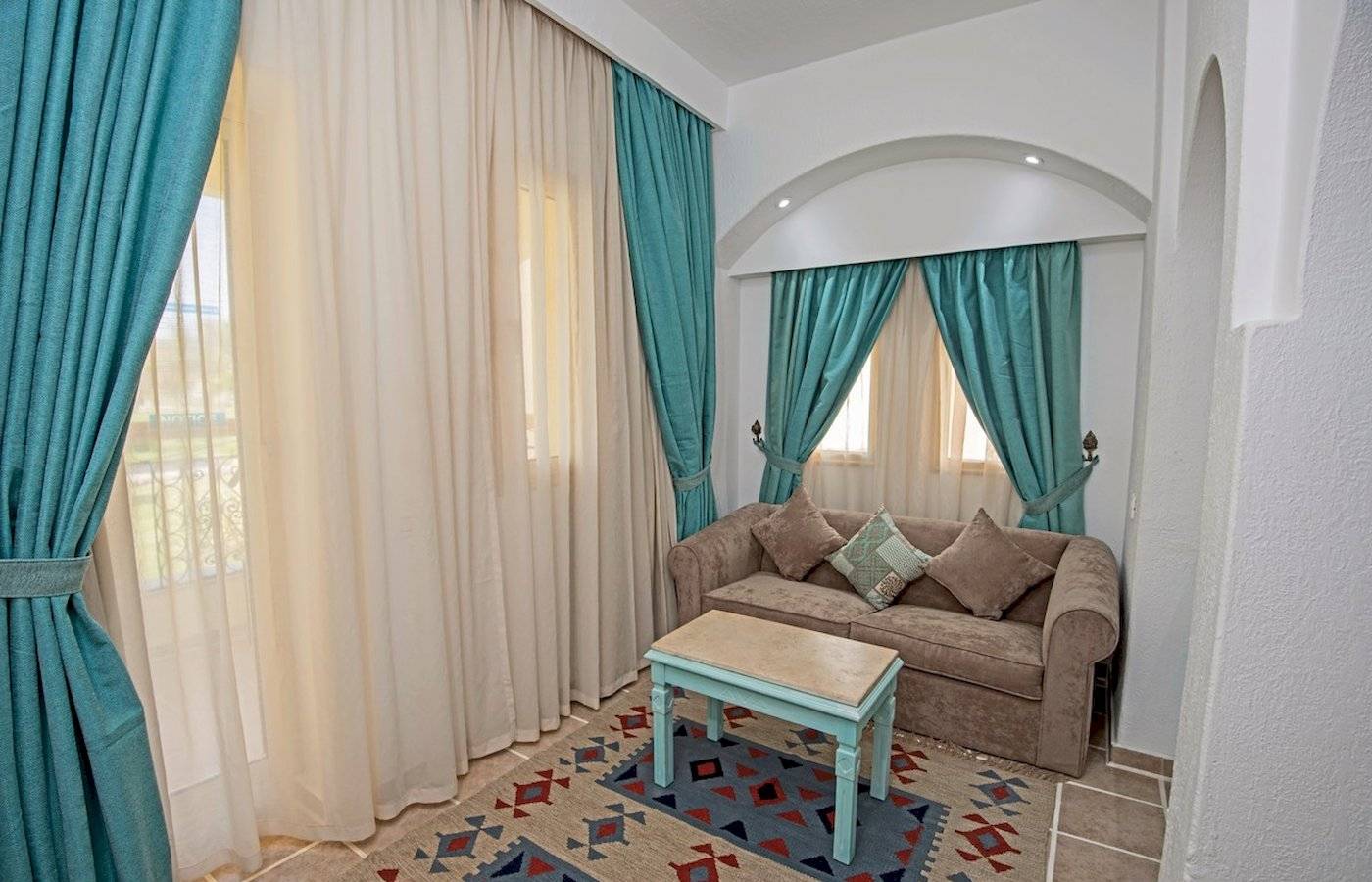 Wohnzimmer mit Sofa, Tisch, blauen Vorhängen und Teppich.