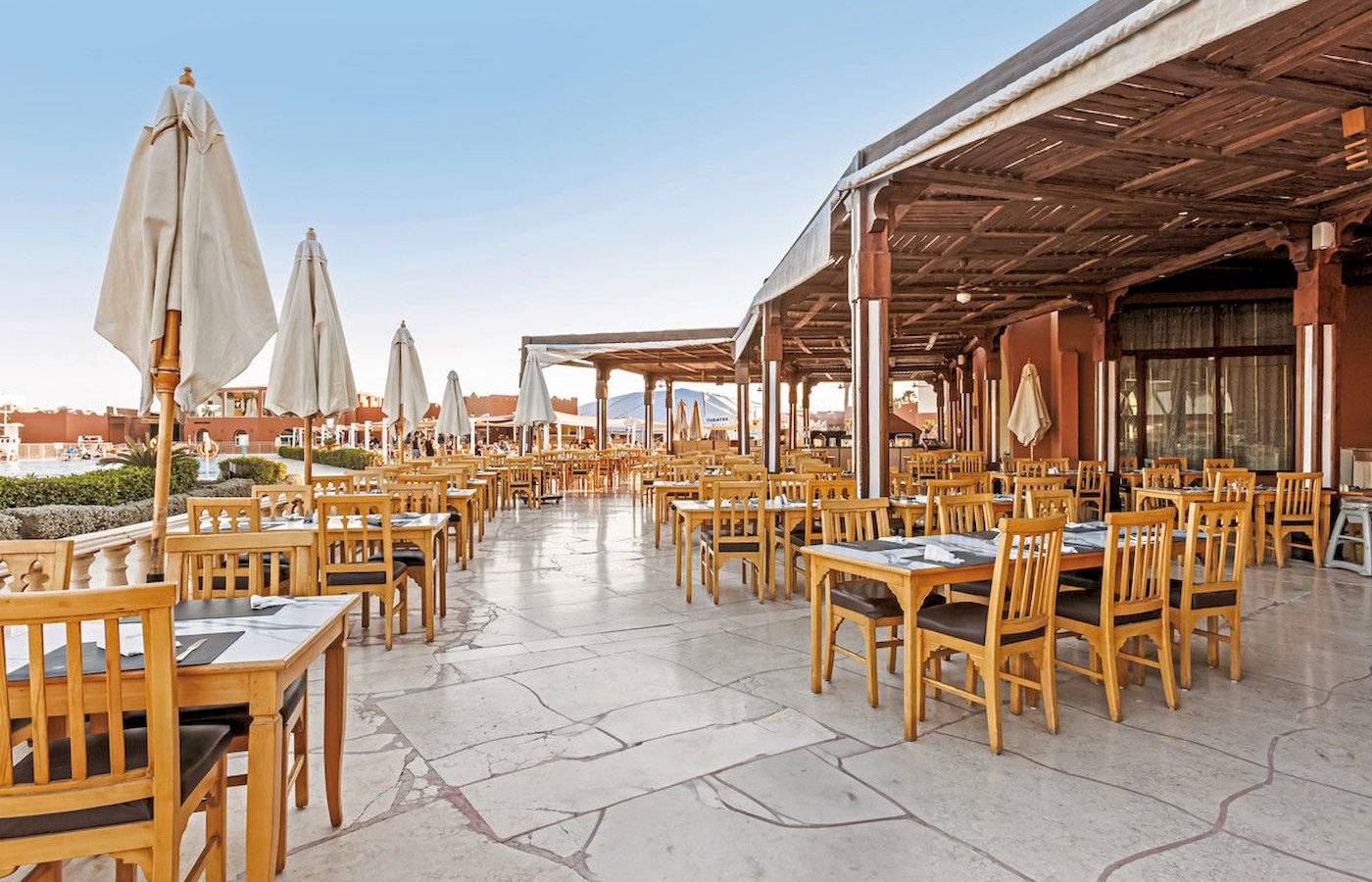 Außenbereich des Restaurants im Sunrise Royal Makadi Resort mit vielen Tischen und Stühlen.