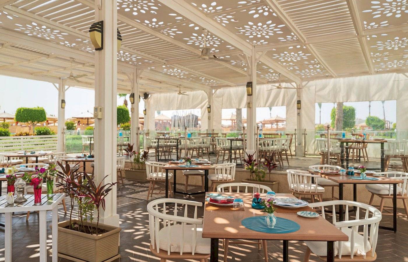 Restaurantbereich des Sunrise Royal Makadi Resorts mit beschatteten Tischen und Stühlen