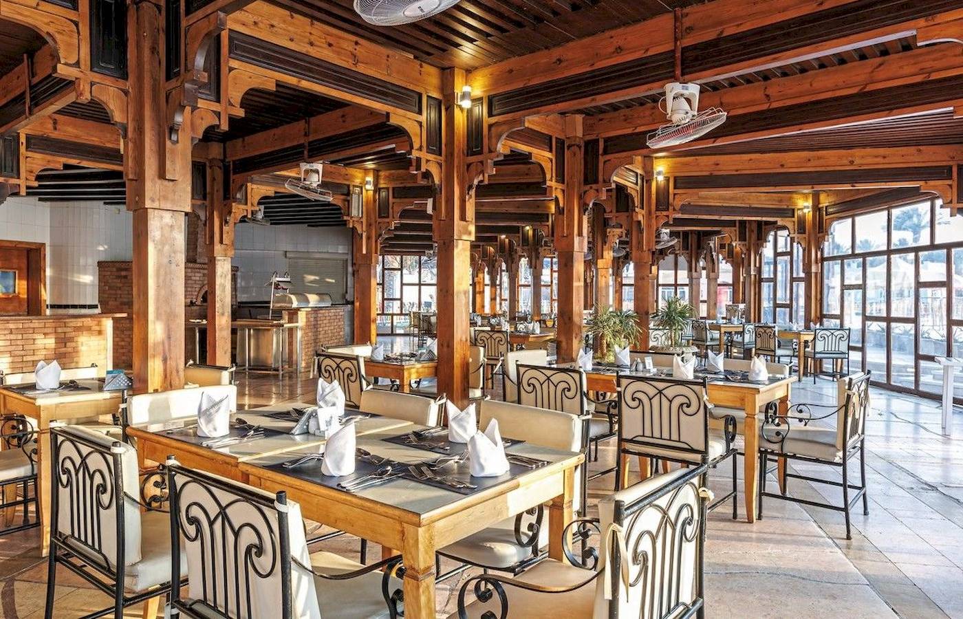 Restaurant des Sunrise Royal Makadi Resort mit Holzmöbeln und Deckenventilatoren.