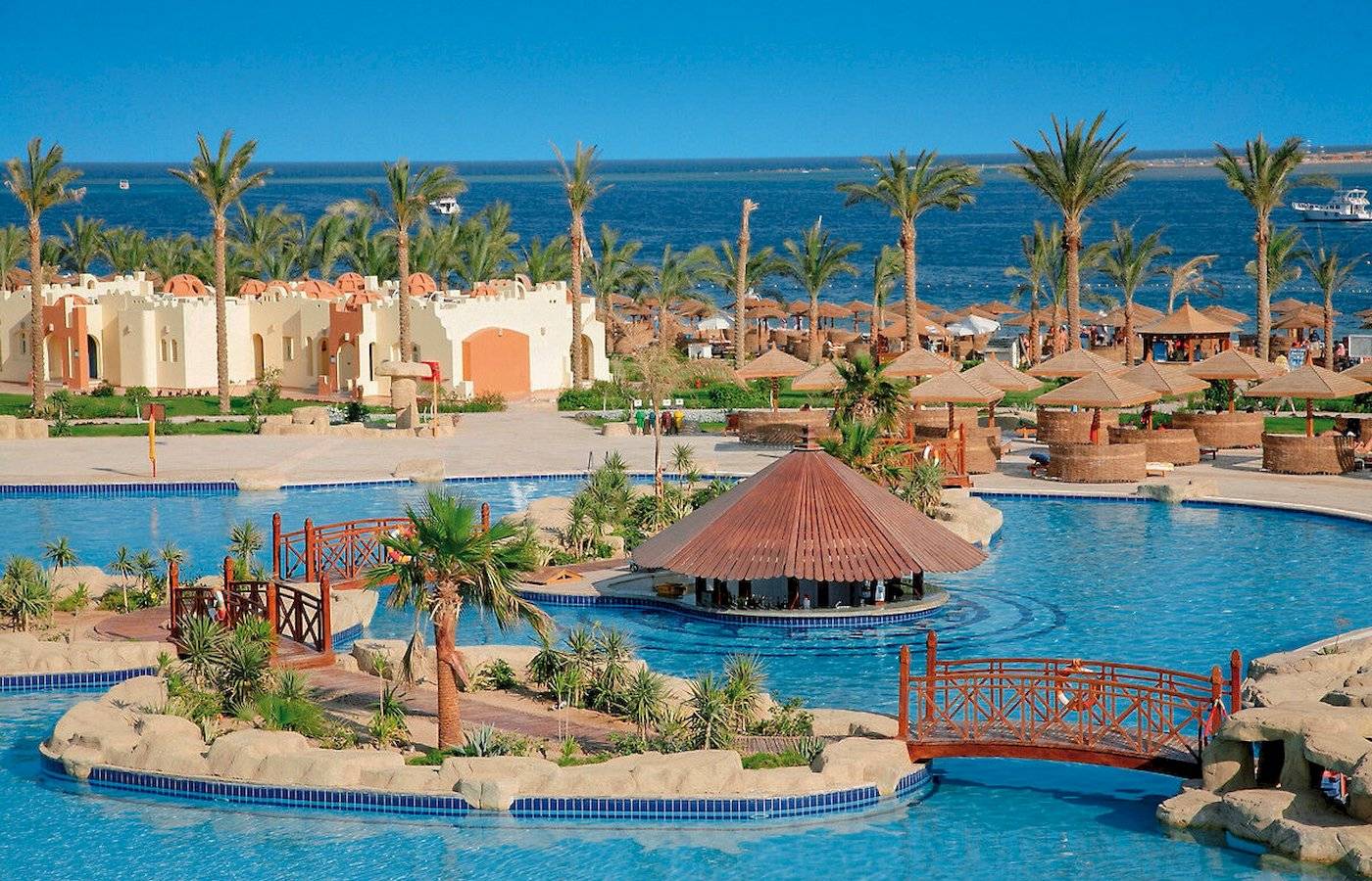 Pool im Sunrise Royal Makadi Resort mit Brücke und Palmen, Blick auf das Meer
