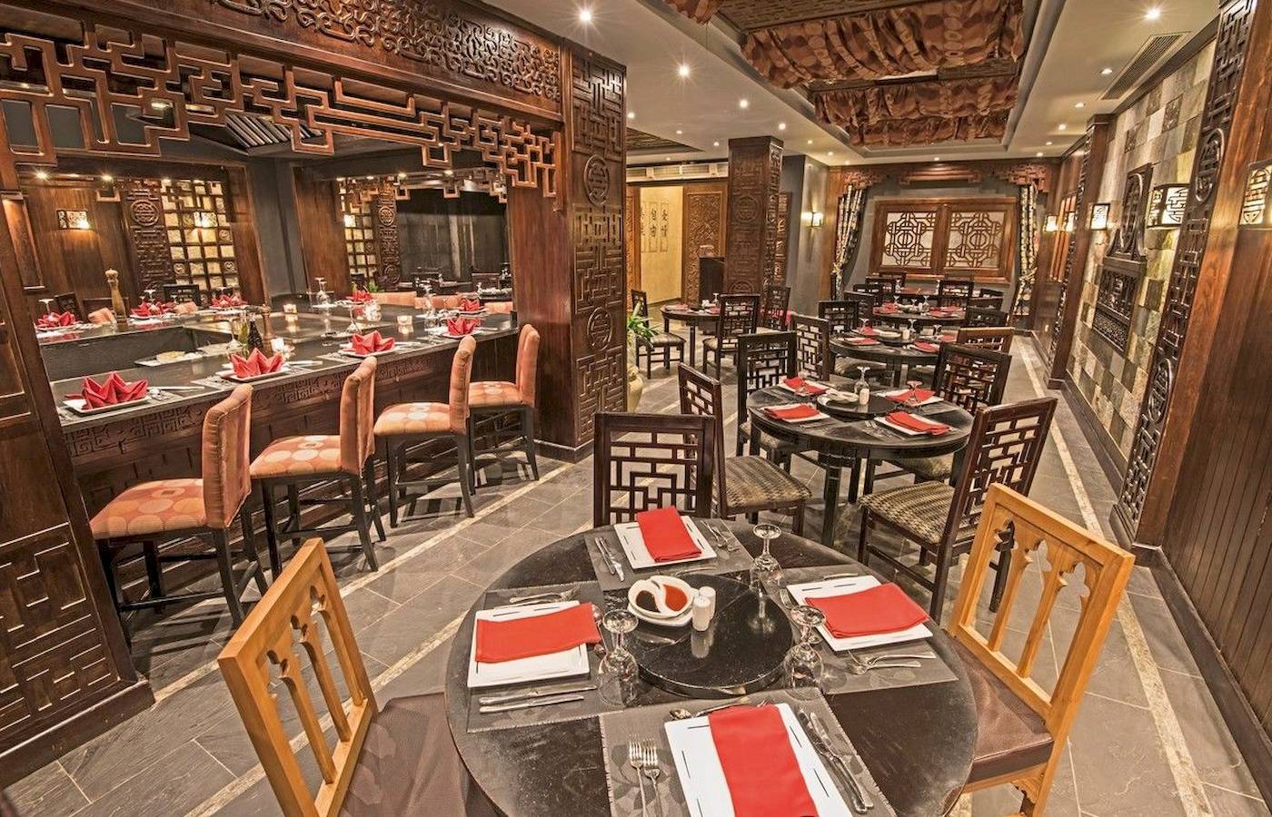 Innenansicht des Restaurants im Sunrise Royal Makadi Resort mit runden Tischen, Stühlen und Holzdesign.