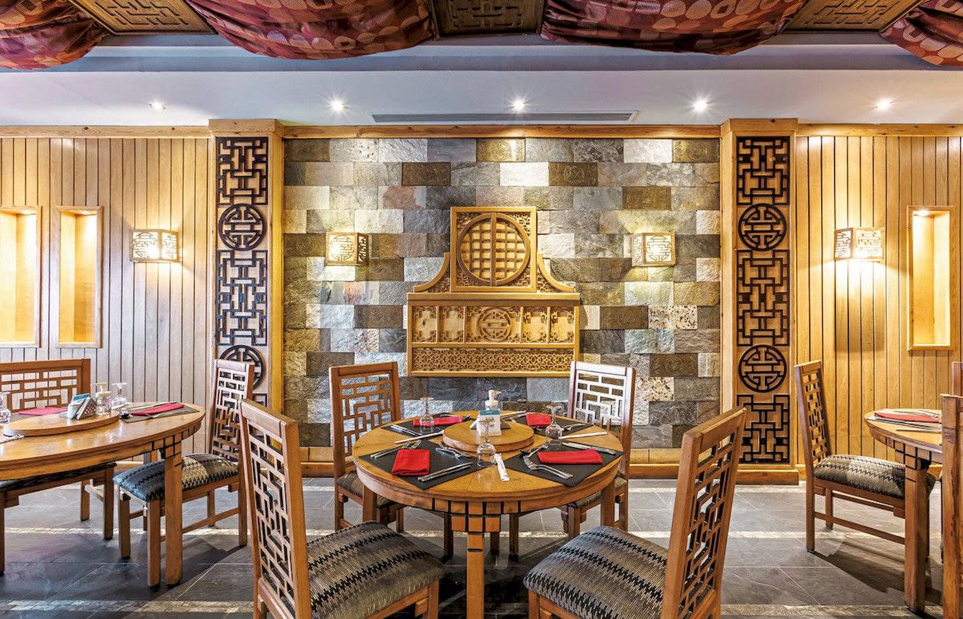 Innenbereich des Sunrise Royal Makadi Resort mit runden Tischen und Holzwänden.