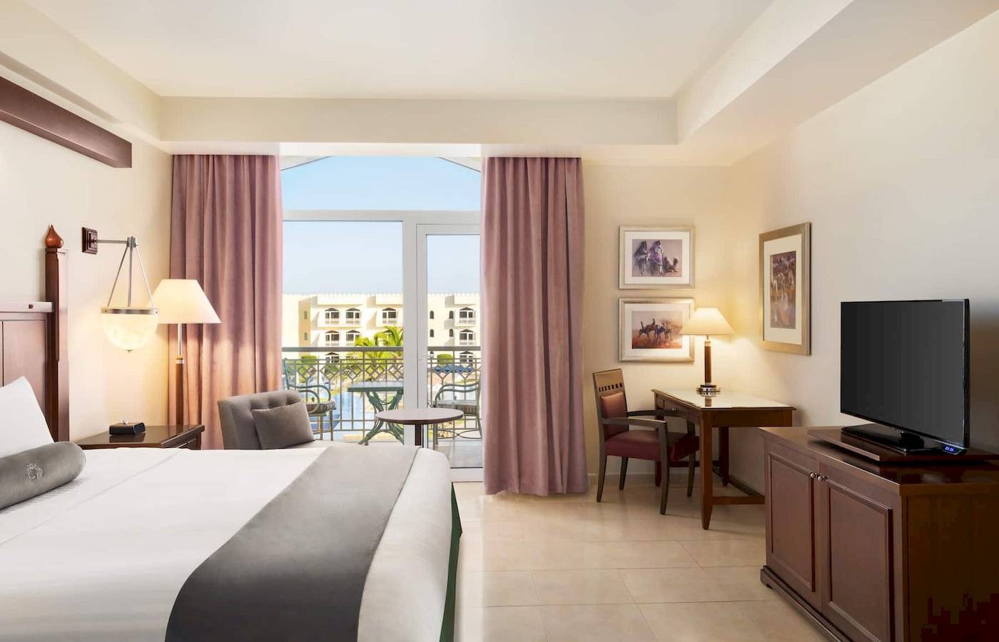 Hotelzimmer im Wyndham Garden Salalah Mirbat mit Balkon, Fernseher und Schreibtisch.