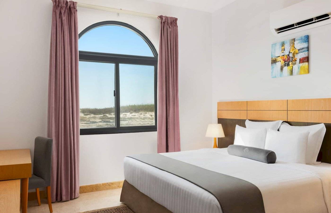 Wyndham Garden Salalah Mirbat Hotel Zimmer mit Bett, Schreibtisch und Fenster mit Meerblick.