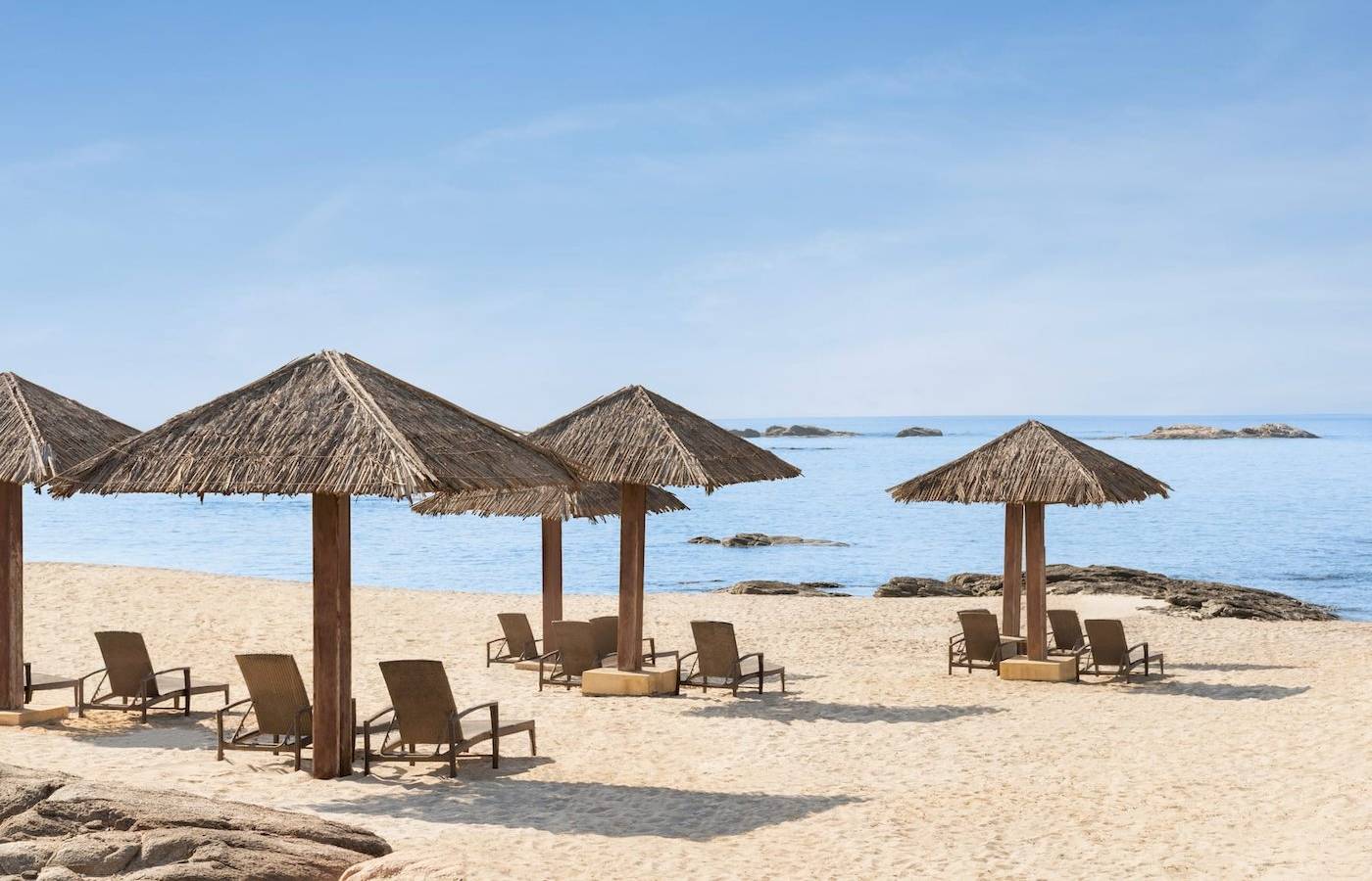 Strand des Wyndham Garden Salalah Mirbat mit Liegen unter Strohdächern
