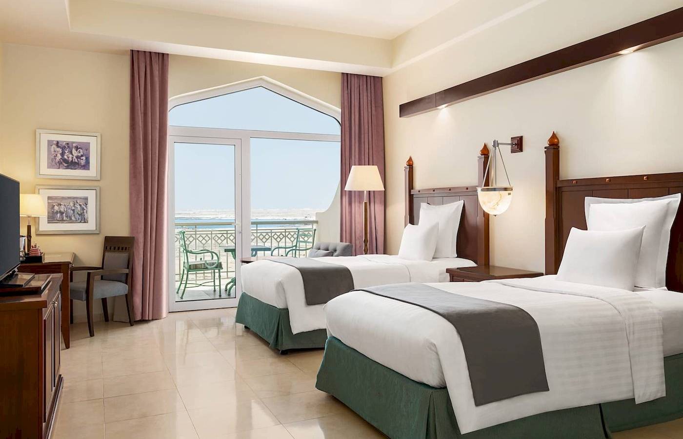 Hotelzimmer mit zwei Betten, Blick auf das Meer und einen Balkon.