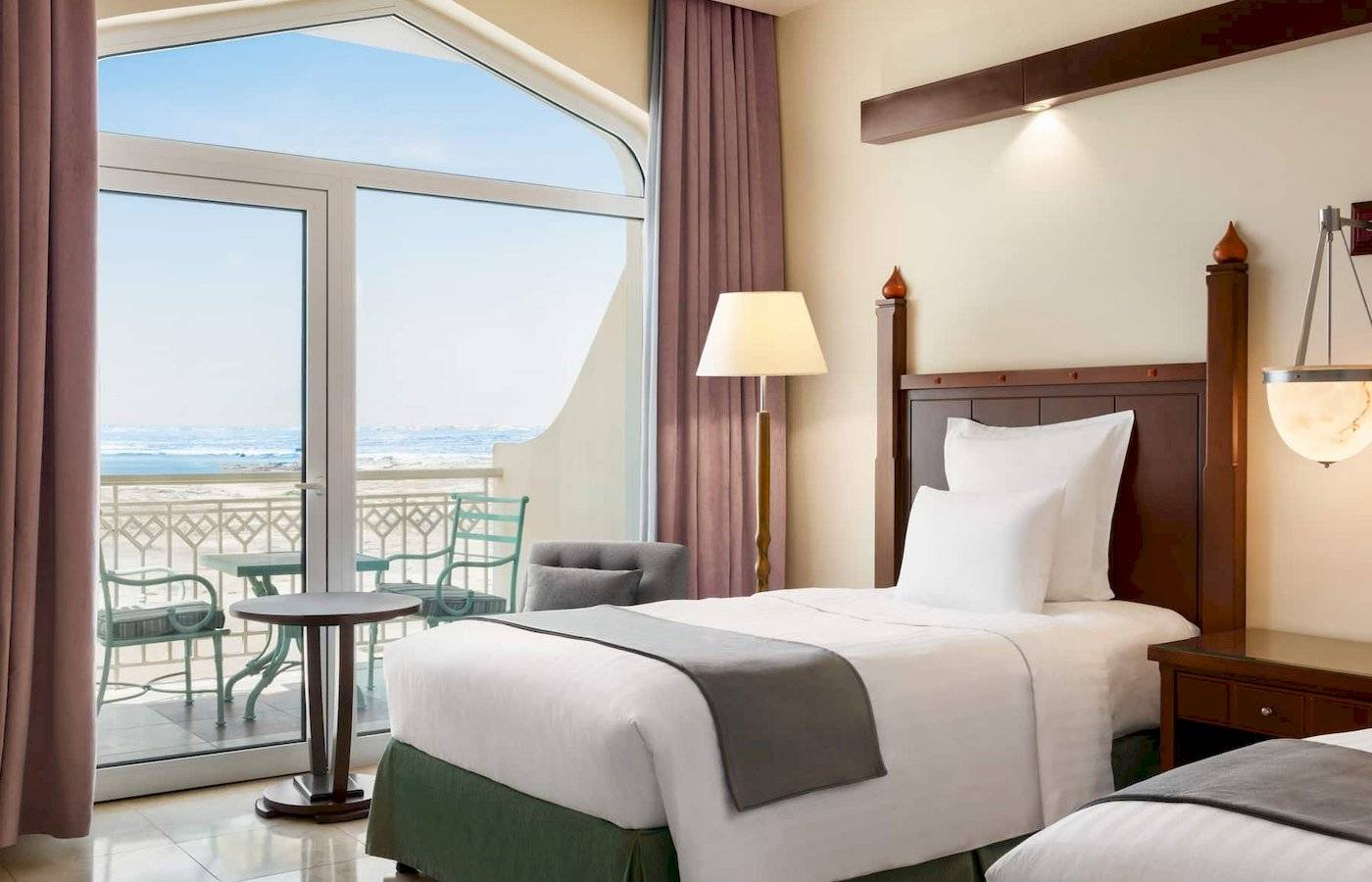 Zimmer im Wyndham Garden Salalah Mirbat Hotel mit Blick auf das Meer von einem Balkon.