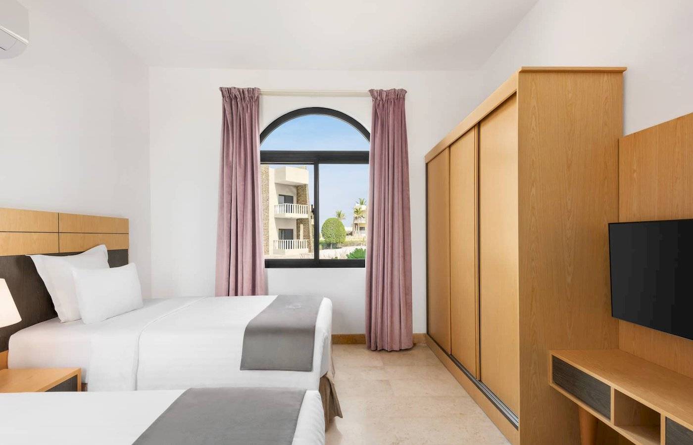 Hotelzimmer im Wyndham Garden Salalah Mirbat mit zwei Betten und Aussichtsfenster.