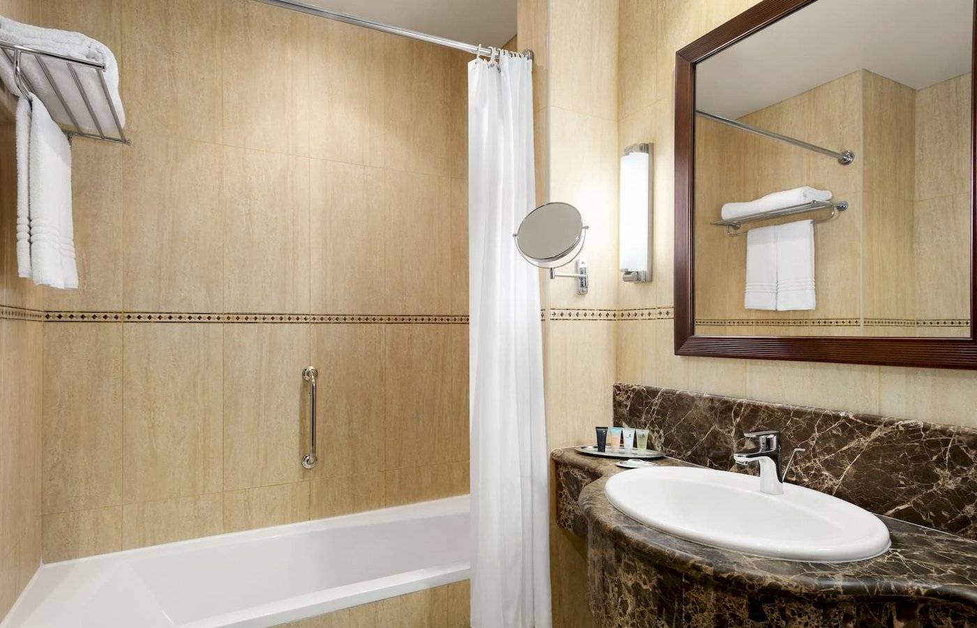 Badezimmer im Wyndham Garden Salalah Mirbat Hotel mit Badewanne, Waschbecken und Spiegel.