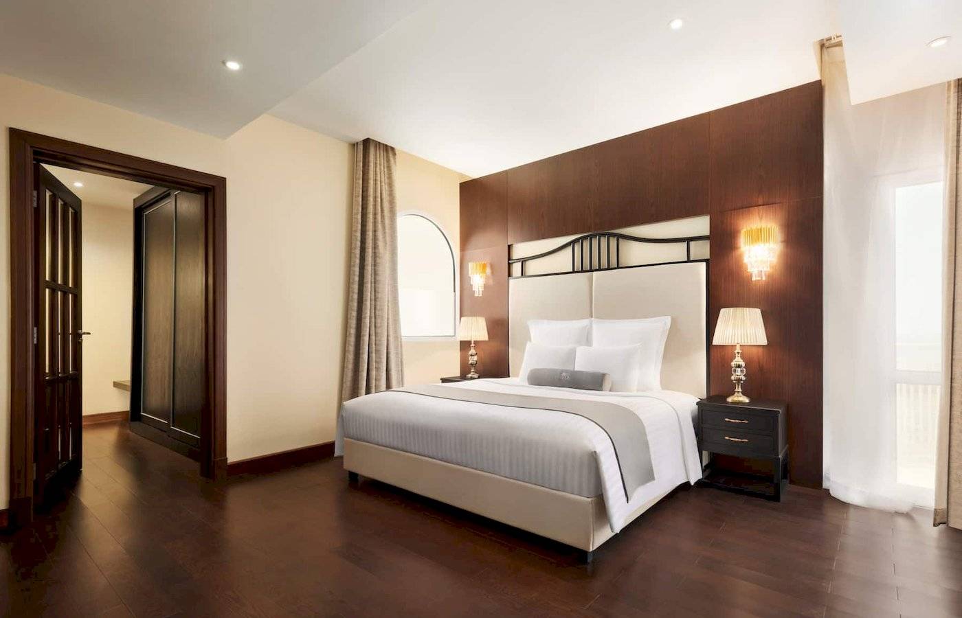 Schlafzimmer im Wyndham Garden Salalah Mirbat Hotel mit Doppelbett, Nachttischen und Lampen.