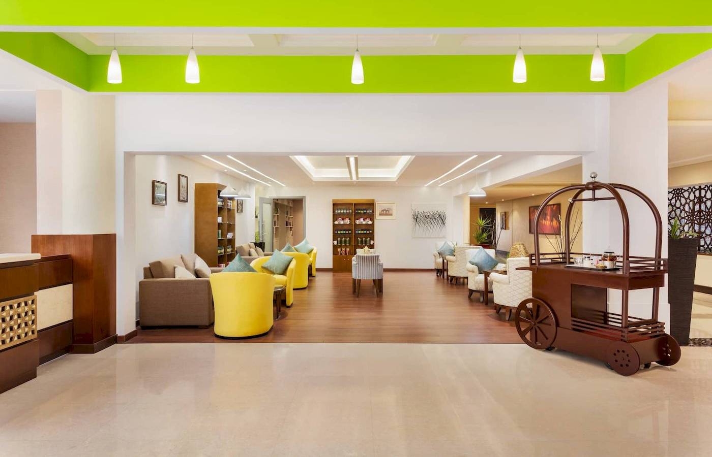 Lobby des Wyndham Garden Salalah Mirbat mit gelben Sesseln und einem Servierwagen